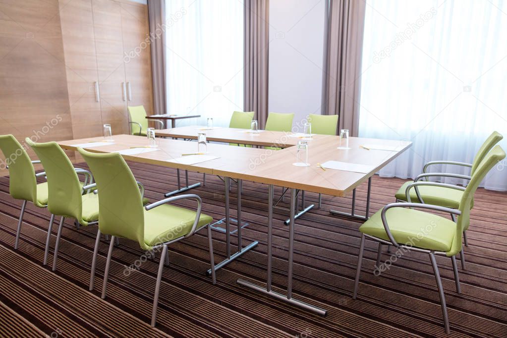 interior of light committee room furnished with modern table and green chairs