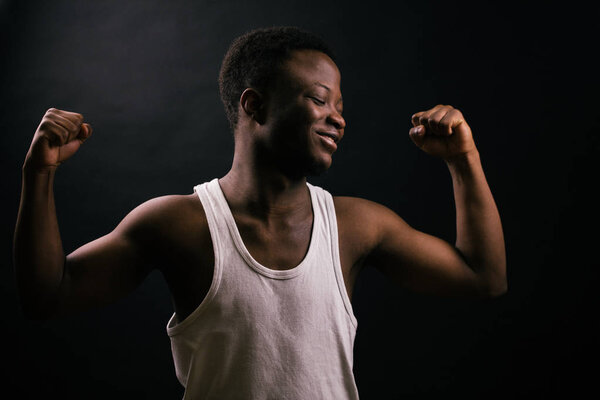 Side view image of happy, crazy young male demonstrating his muscules.keep fit. happiness of training.smirk.