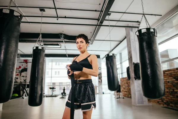 Bonito boxeador con cuerpo delgado desenrollando vendaje después de entrenamiento duro — Foto de Stock