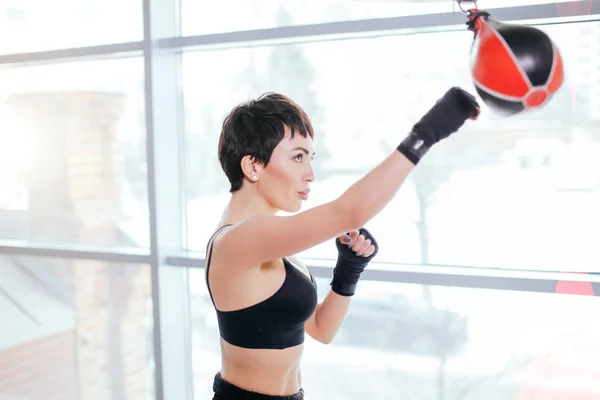 Joven kickboxer haciendo ejercicios con bolsa de velocidad en el estudio . — Foto de Stock