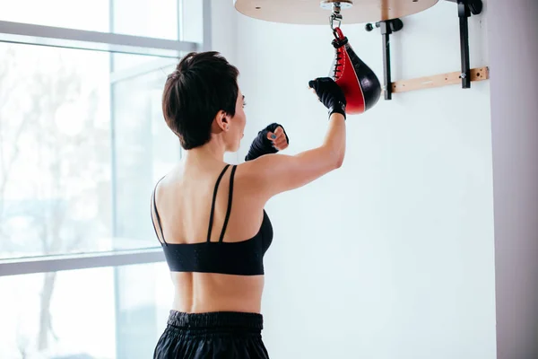 Vista trasera de la mujer enérgica practicando boxeo golpes en el gimnasio —  Fotos de Stock
