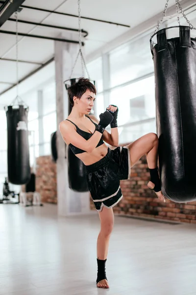 Imagen de vista lateral del luchador muscular femenino con la pierna levantada y los puños apretados —  Fotos de Stock