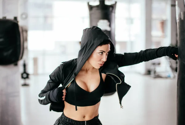 Entrenamiento femenino agresivo patadas altas en saco de boxeo en el gimnasio —  Fotos de Stock