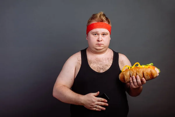 デブ男は、腹に手を握って不健康なハンバーガーを食べるための準備 — ストック写真
