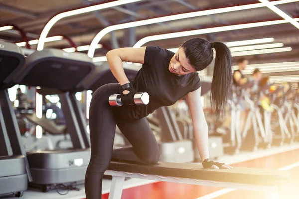 Femme flexion des muscles avec haltère sur banc dans la salle de gym — Photo