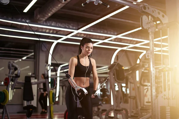 Fitte Frau führt Übung mit Trainingsgerät Cable Crossover im Fitnessstudio durch — Stockfoto