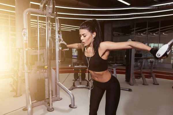 Fit kvinna utföra motion med träningsmaskin kabel Crossover i gym — Stockfoto