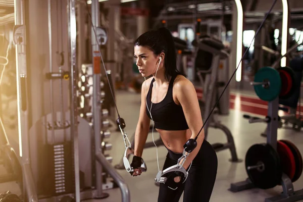 Fit kvinna utföra motion med träningsmaskin kabel Crossover i gym — Stockfoto