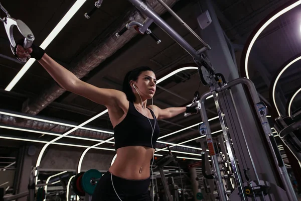 Fit kvinna utföra motion med träningsmaskin kabel Crossover i gym — Stockfoto