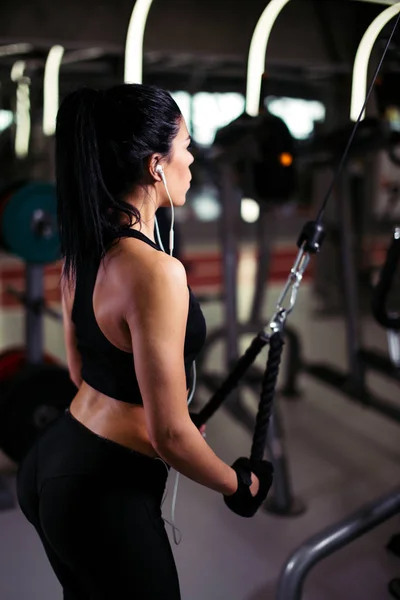 Achteraanzicht fitte vrouw uit te voeren oefening met oefening-machine Kabel Crossover in de sportschool — Stockfoto