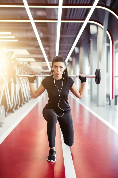 Meisje doet lunges met lange halter in moderne sportschool — Stockfoto