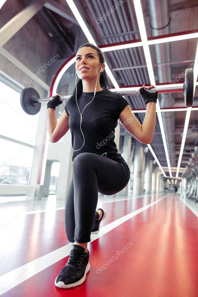 girl doing lunges with barbell in modern gym
