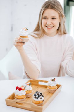 Mutlu gülümseyen kadın ejoying fırından yeni çıkmış cupcakes.