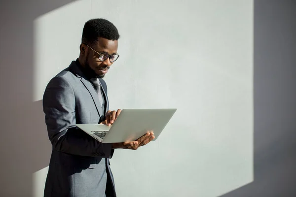 Colega de trabalho africano usando óculos e usando laptop no escritório — Fotografia de Stock