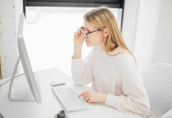 Mujer trabajando en la oficina, sentada en el escritorio, usando la computadora y mirando en la pantalla — Foto de Stock