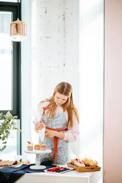 Mujer bastante joven decorando cupcakes en su cocina —  Fotos de Stock