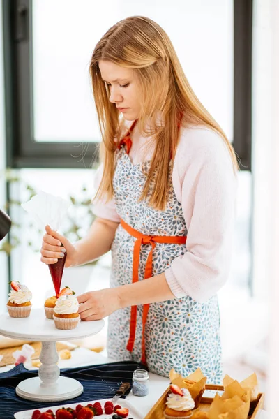 Confiseur décorant les cupcakes avec une garniture rouge à l'aide d'une seringue à pâtisserie — Photo