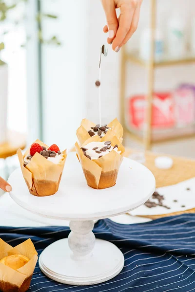 Primer plano de pastelería cocinero mano decoración cupcakes de chocolate en polvo en la cocina — Foto de Stock