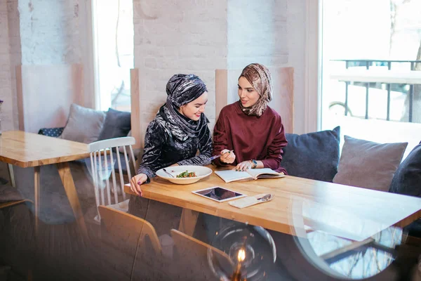 Duas mulheres de negócios muçulmanas bonitas no cachecol cabeça escrever no caderno — Fotografia de Stock