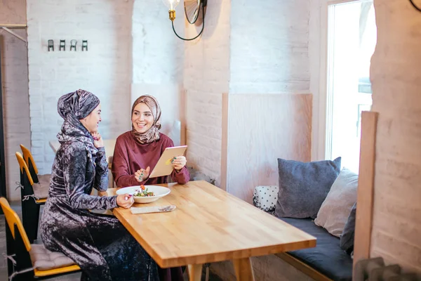 Dos mujeres musulmanas en la cafetería, comprar en línea usando tableta electrónica — Foto de Stock