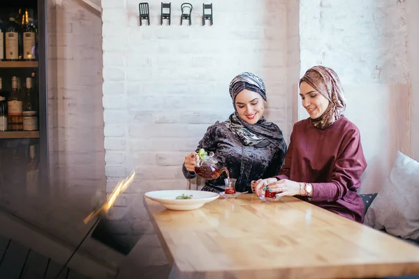 Dva běloši Muslimská žena pít čaj v kavárně — Stock fotografie