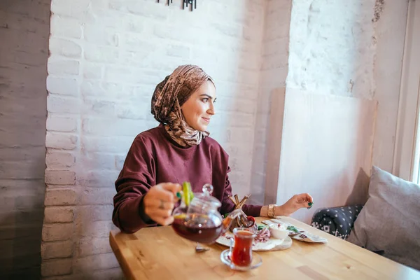 Азиатская мусульманка наливает чай на чашку — стоковое фото
