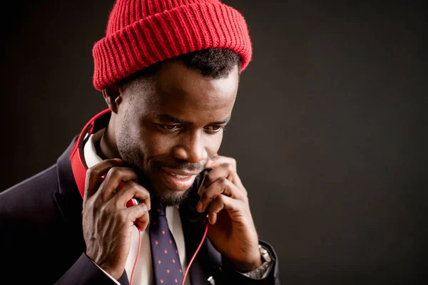 close up side view image of African guy wearing red cap and headphones