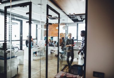 cam duvarlı modern ofiste çalışan genç insanlar