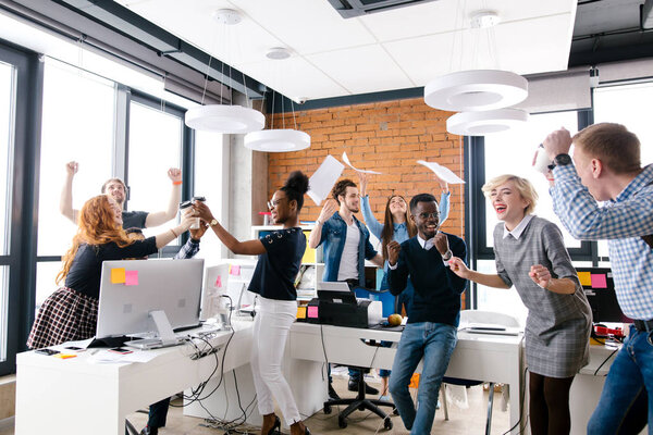 Молодая многонациональная группа офисных работников празднует триумф
