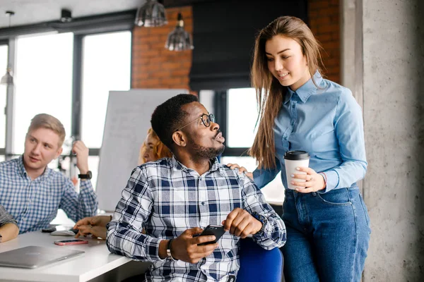 Oplettend aangename vrouw in blauw shirt en spijkerbroek is het geven van koffie voor de mens — Stockfoto