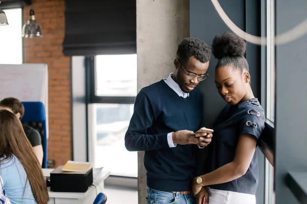 Giovane coppia afro in abito casual utilizzando il telefono cellulare — Foto Stock
