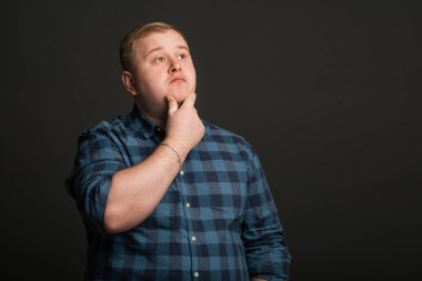 Şişman beyaz adam düşünüyor ve boşluğa bakıyor.