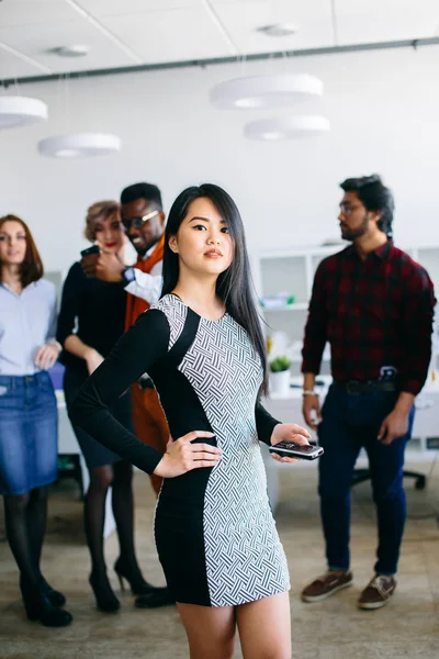 Inteligente asiático gerente celebración de su móvil posando a la cámara — Foto de Stock