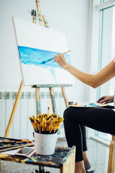 Pintor, chica europea dibujando paisaje marino sobre lienzo en su taller. Concepto de clases de bellas artes — Foto de Stock