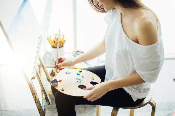 Женщина-художник рисует картину в хорошо освещенной студии
