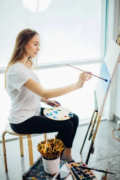 Pittore, ragazza europea che disegna paesaggi marini su tela nel suo laboratorio. Concetto di classi di belle arti — Foto Stock