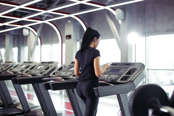 Deportiva usando smartphone para la aplicación de entrenamiento mientras trota en la cinta de correr — Foto de Stock
