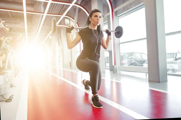 Flicka gör lungor med skivstång i modernt gym — Stockfoto