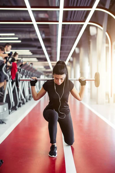 Mädchen beim Ausfallschritt mit Langhantel in moderner Turnhalle — Stockfoto