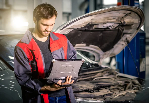 Mechanik badający silnik samochodowy z pomocą laptopa — Zdjęcie stockowe