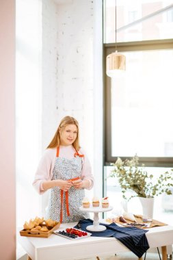 Kameraya bakarak capcakes, hazırlama genç sarışın kız,