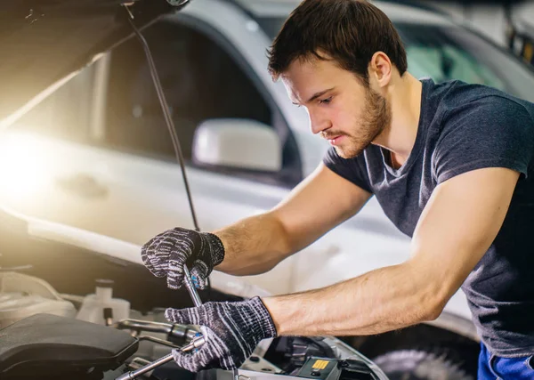 Mécanicien travaillant sous capot de voiture dans garage de réparation — Photo