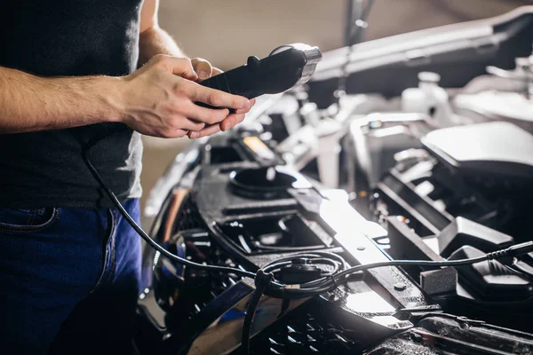 mechanic testing electrical system on automobile