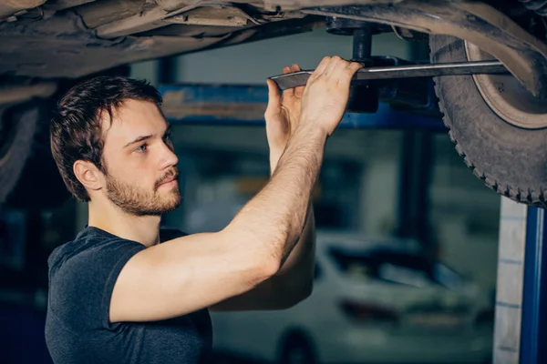 Mekaniker under bil i garageundersökning däck och tekniskt skick — Stockfoto