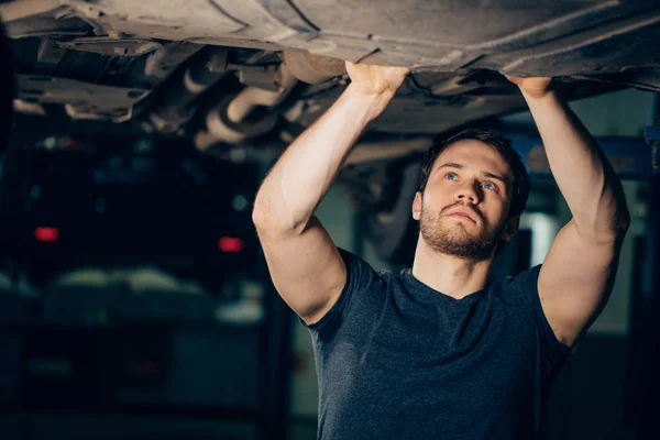Mechanik pod samochodem w garażu badania opon i stanu technicznego — Zdjęcie stockowe