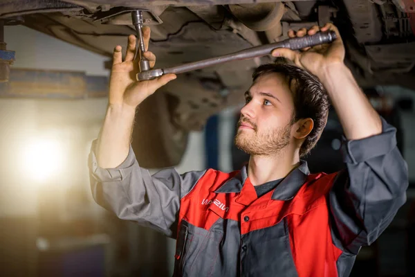 Meccanico sotto auto in garage esame pneumatici e condizioni tecniche — Foto Stock