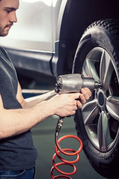 Meccanico che cambia ruota dell'automobile nel garage di riparazione auto — Foto Stock