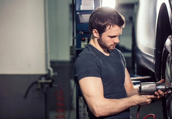 Mekaniker föränderliga bil rullar i auto reparera garage — Stockfoto