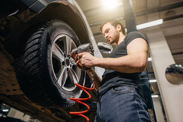 Mecânico mudança roda de carro na oficina de reparação de automóveis — Fotografia de Stock