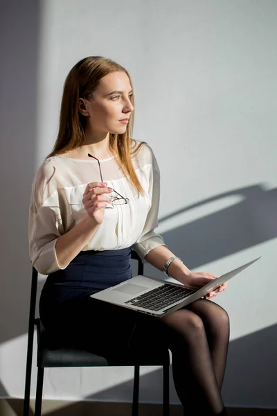 Белая женщина в деловой одежде сидит на стуле с ноутбуком — стоковое фото